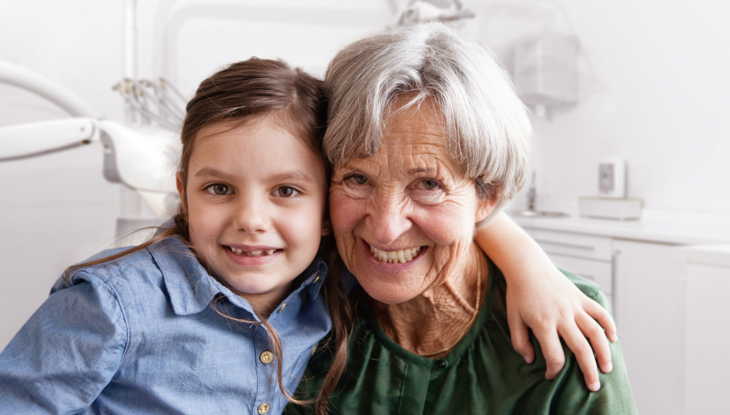 Older woman and little girl arm in arm, smiling