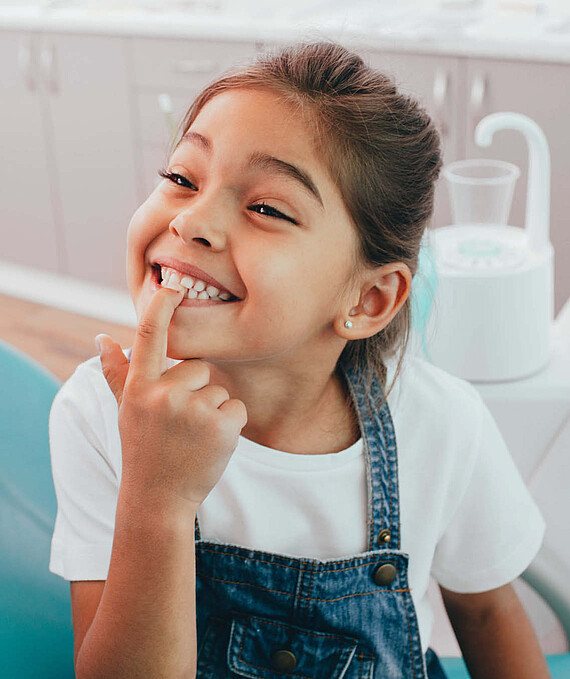 Une jeune fille montre ses dents en souriant.